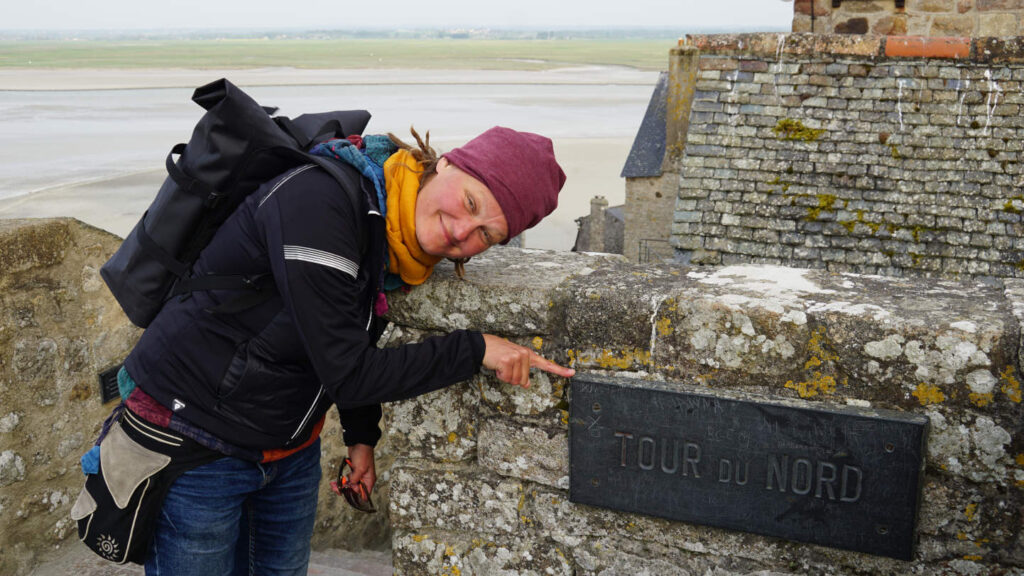 Frau zeigt belustigt auf das Schild "Tour du Nord"