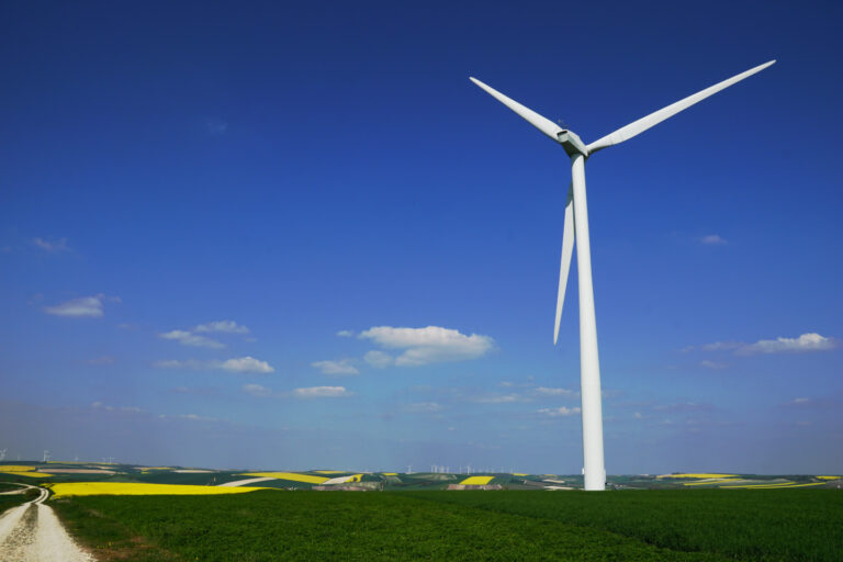 riesiges modernes Windrad in einer Landschaft voller grüner und gelber Felder