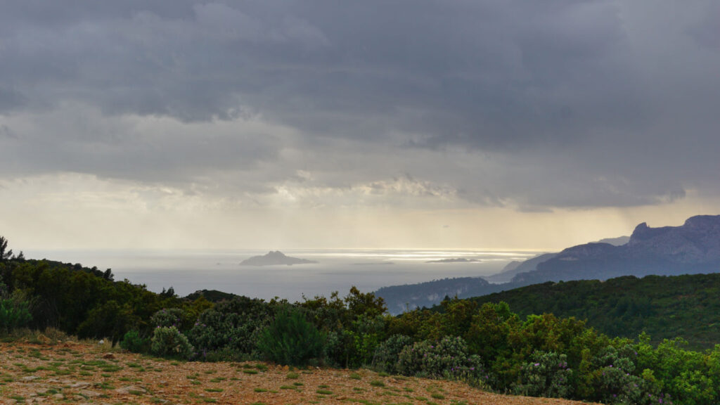 Ausblick auf das Meer und ein vorgelagerte Insel, über die Regenwolken hinweg ziehen