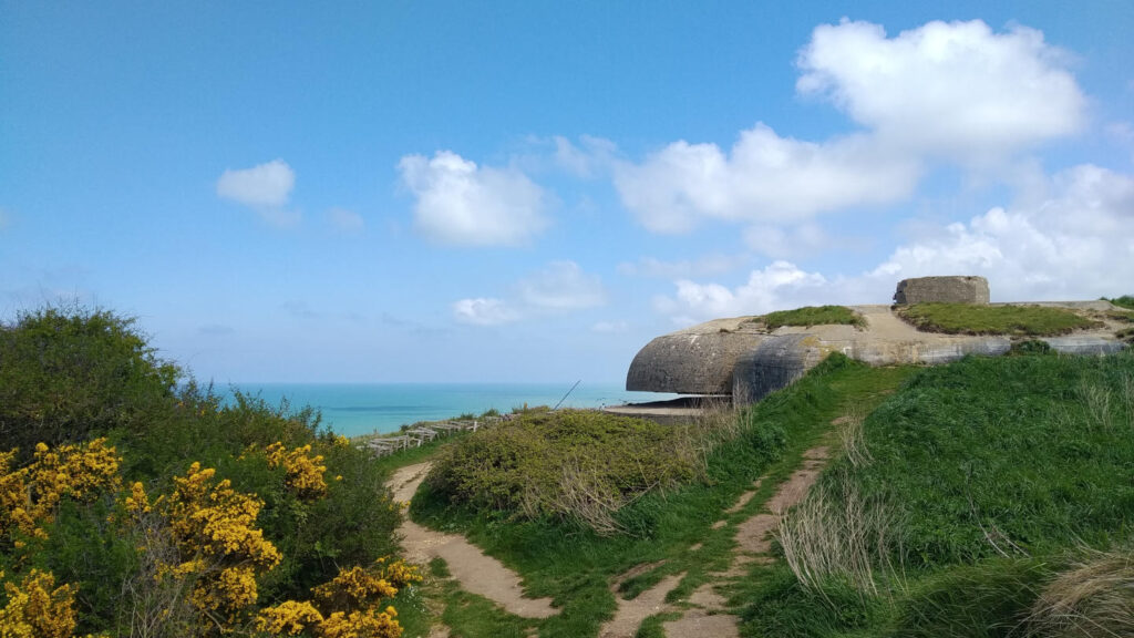 Betonbunker mit gelbblühenden Ginsterbüschen und Aussicht auf das Meer am Kap Fagnet