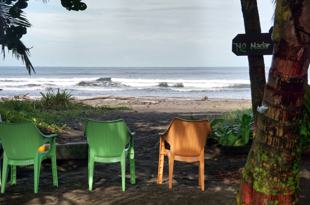 Strand mit drei bunten Plastikstühlen, Hotel El Icaco in Tortuguero, Costa Rica