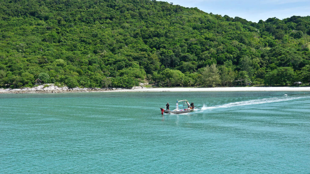 Longtail Boot fährt vor einer Insel