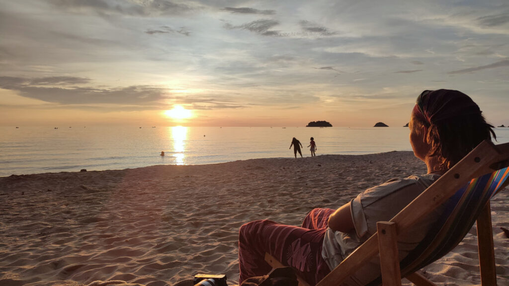 Frau im Liegestuhl am Strand bewundert den Sonnenuntergang, Lonely Beach, Ko Chang, Thailand