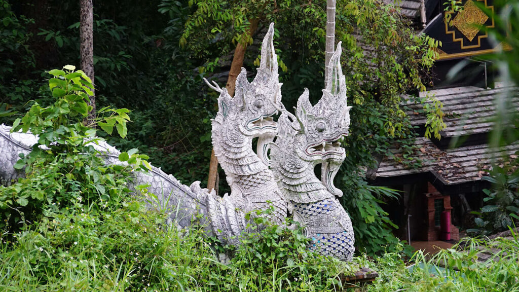 Naga, Statuen und Steinfiguren mitten im Dschungel im Waltdtempel Wat Pha Lat in der Umgebung von Chiang Mai, Thailand