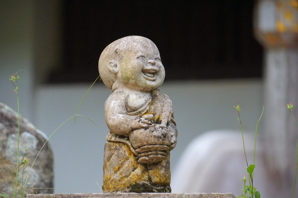 lachender kleiner Mönch - Steinfigur im Waldtempel Wat Pha Lat in der Umgebung von Chiang Mai, Thailand