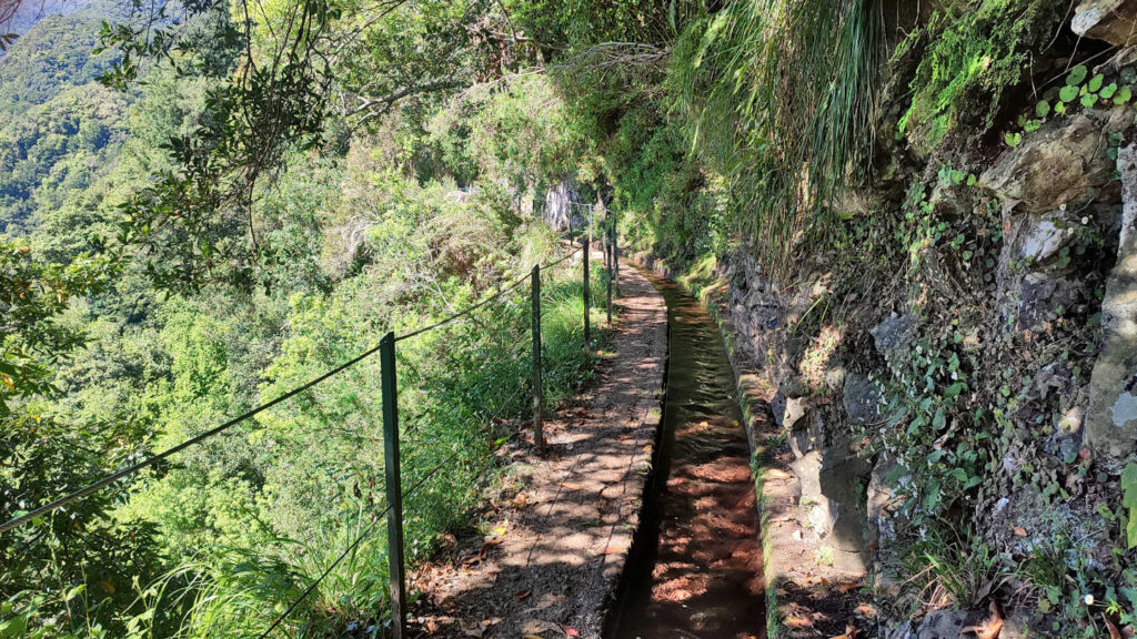 schmaler Weg neben der Levada do Rei an einer Felswand entlang, der mit einem Zaun abgesichert ist, Insel Madeira