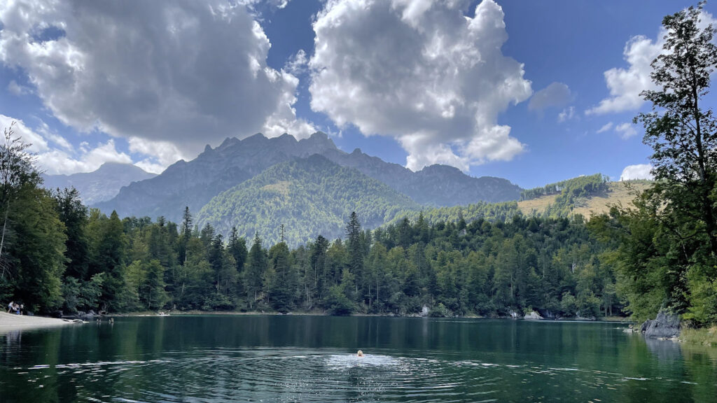 Frau schwimmt mitten im Großen Ödsee mit Ausblick auf ein gewaltiges Bergpanorama, Almtal in Oberösterreich